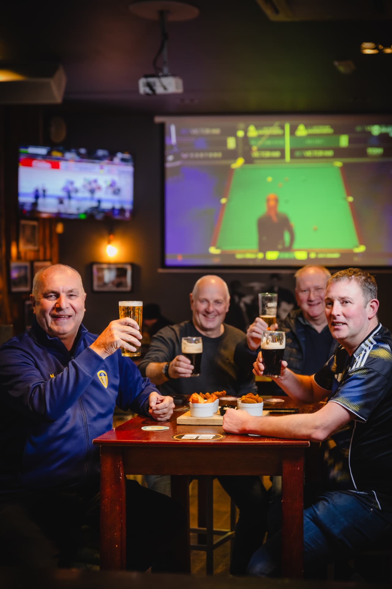 Leeds fans raising pints at a table in Toast