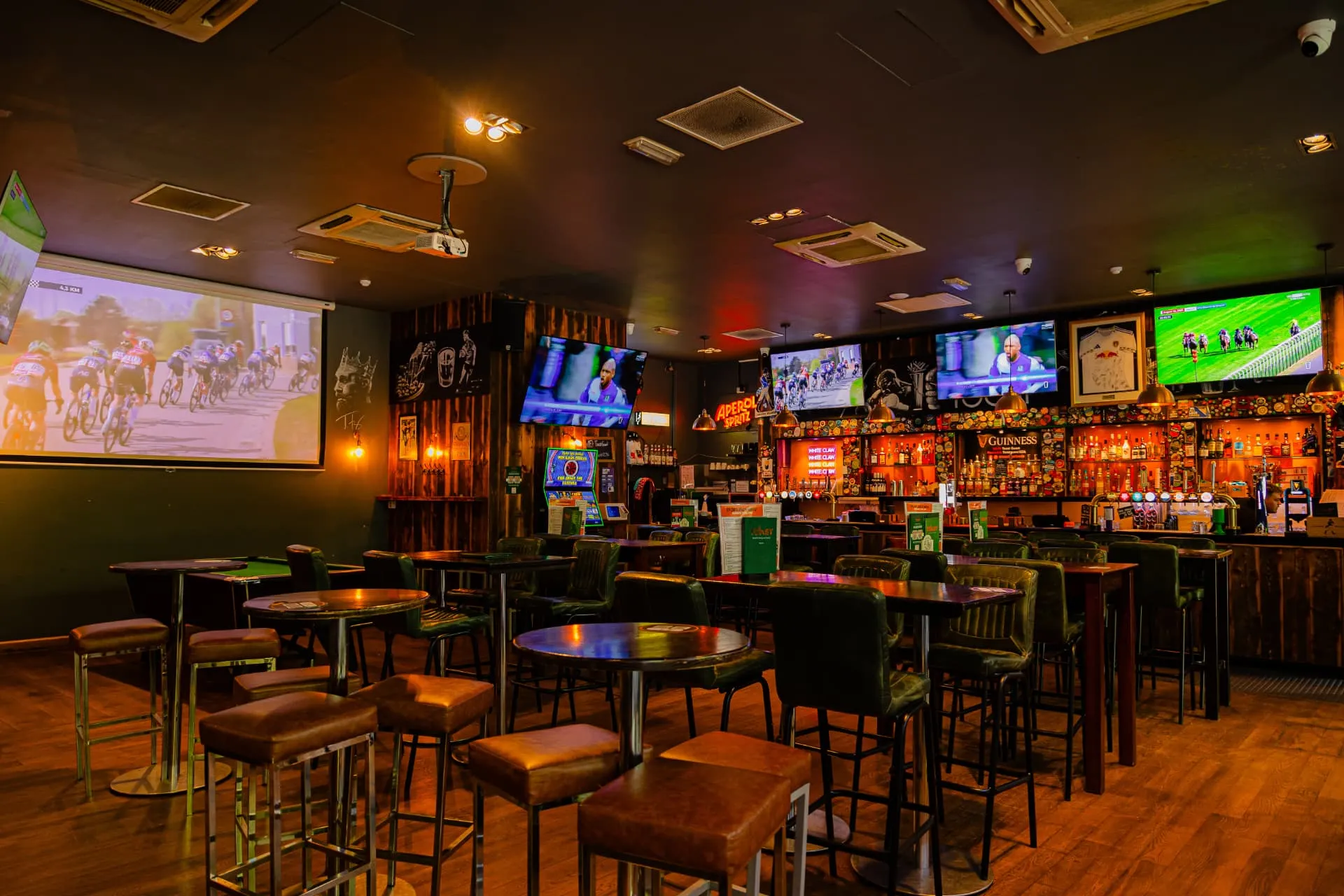 Inside Toast Leeds: big screens showing football and rugby above green booths